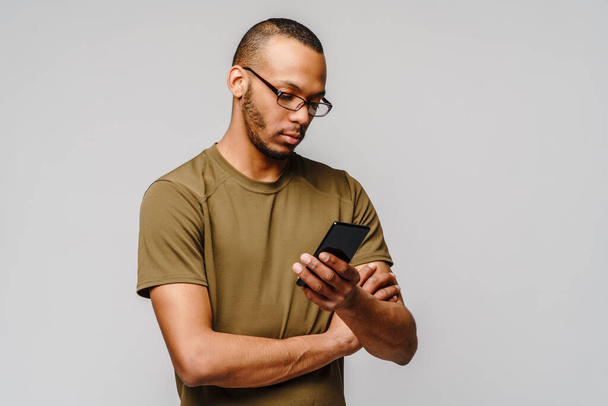 Portrait of a young african american man wearing glasses holding cell phone - Fotografie, Obrázek
