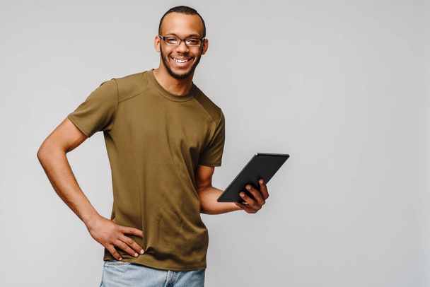 Portrait of a young african american man wearing glasses holding tablet pc pad - Foto, imagen