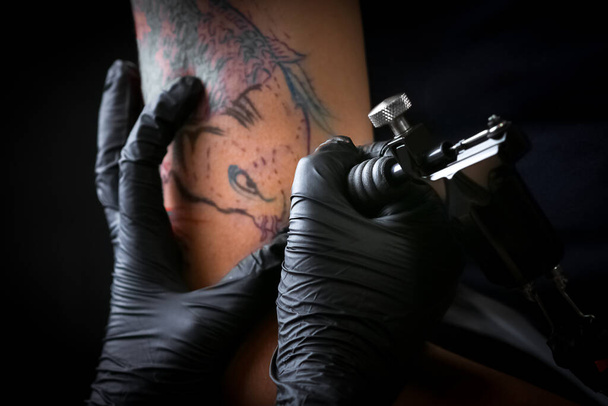 Female tattoo artist making tattoo on a men`s arm - Fotoğraf, Görsel