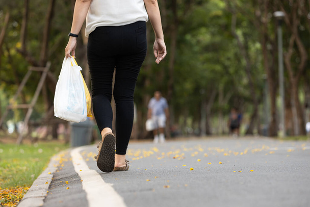 Az újrahasznosítás koncepciója, a hulladék mennyiségének csökkentése, az ázsiai nő, aki egy műanyag zacskót hord magánál, amit egy korábbi, újrahasználatra szánt bevásárlókonferencián használt, a nő az utcán sétál, és műanyag zacskót tart az élelmiszerekkel  - Fotó, kép