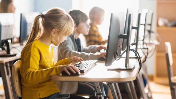 Elementary School Computer Science Classroom: Diverse Group of Little Smart Schoolchildren using Personal Computers, Learn Informatics, Internet Safety, Programming Language for Software Coding - 写真・画像