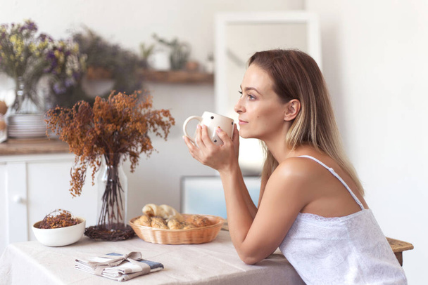 Young beautiful woman having breakfast in the morning in the kitchen. - Photo, Image