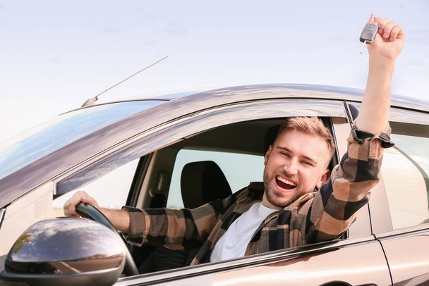 Onnellinen nuori mies, jolla on avain uudessa autossaan - Valokuva, kuva