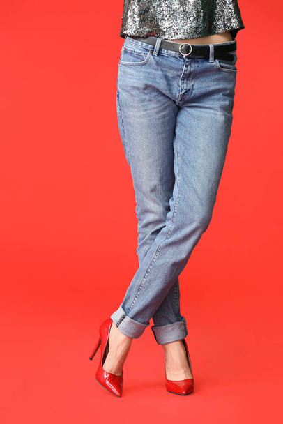 Beautiful young woman in jeans on color background - Фото, зображення