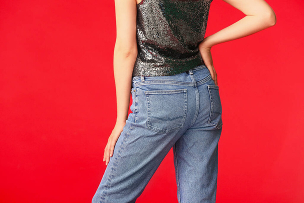 Krásná mladá žena v džínách na barevném pozadí - Fotografie, Obrázek