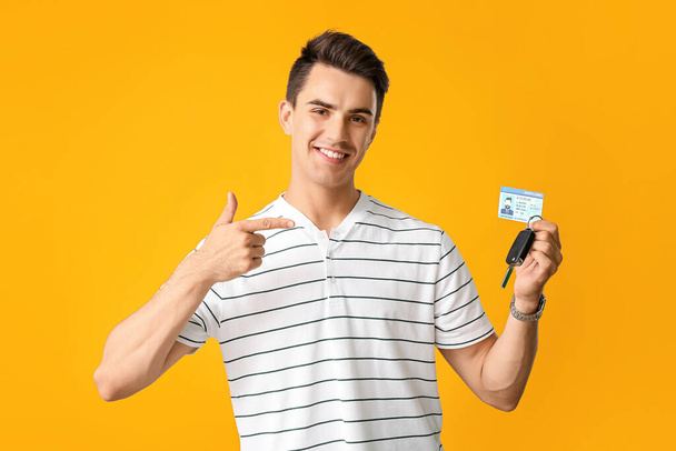 Young man with driving license and car key on color background - Foto, imagen