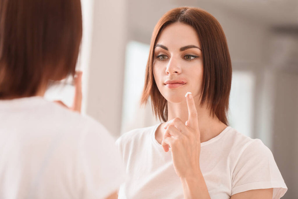 Young woman with cold sore applying remedy at home - Photo, Image
