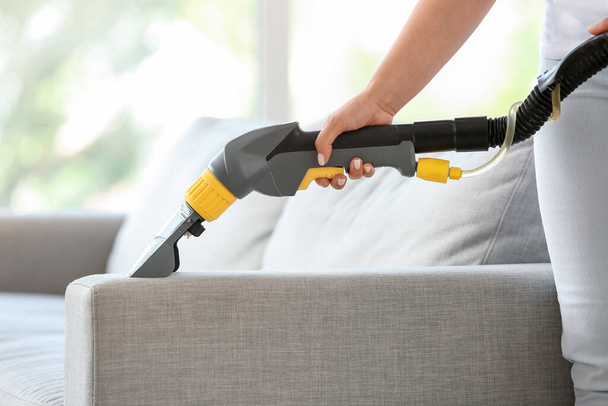 Woman removing dirt from sofa at home - Foto, Bild