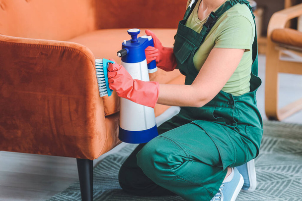 Pracownik pralni chemicznej usuwający brud z sofy w domu - Zdjęcie, obraz