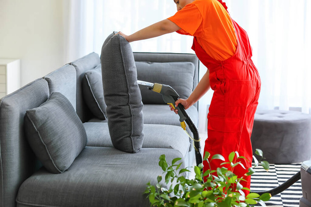 Empleado de la tintorería quitar la suciedad del sofá en casa - Foto, imagen