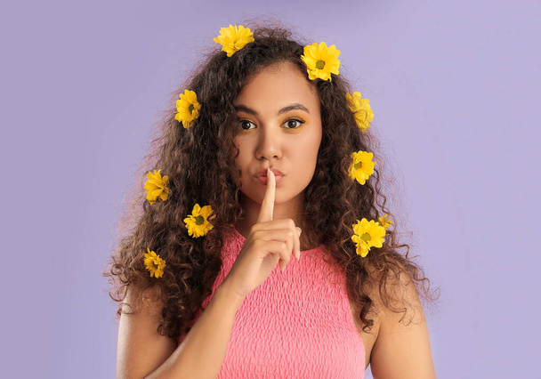 Fiatal afro-amerikai nő gyönyörű szemhéjak és virágok a haját a színes háttér - Fotó, kép