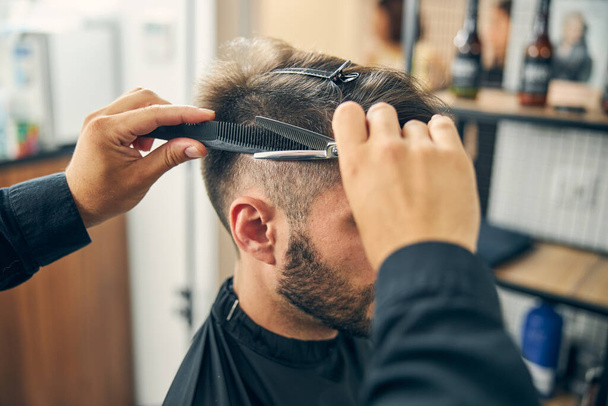 Close up of barber cutting hair in barbershop - Photo, Image
