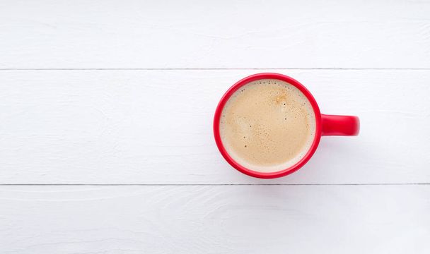 una taza roja con café sobre una mesa de madera blanca - Foto, imagen
