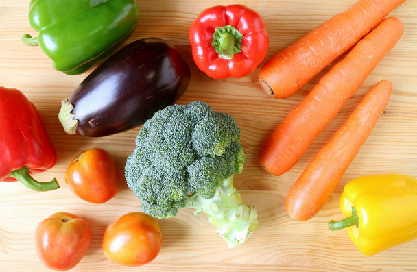 Assortiment de légumes frais colorés éparpillés sur fond en bois - Photo, image