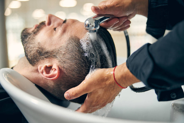 Relaxed young male person enjoying salon beauty procedure - 写真・画像