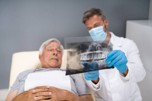 Dentist Examining Dental Xray Of Old Senior - Foto, Imagen