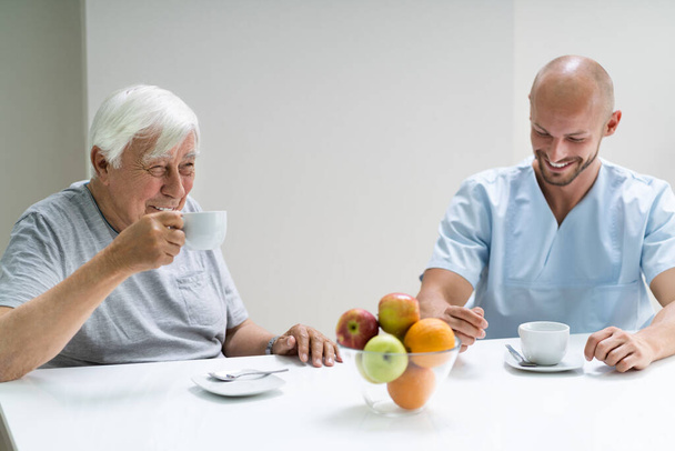 Caretaker In Retirement Home With Elder Man - Foto, Bild