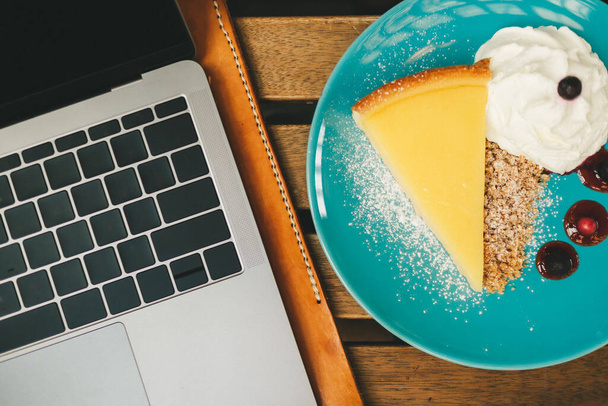 Top view of laptop on the desk with cheesecake in Concept of happy working. - Φωτογραφία, εικόνα