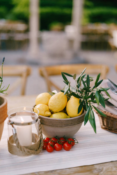 Diepe plaat met citroenen op tafel met een takje kerstomaten op een wazige achtergrond. - Foto, afbeelding
