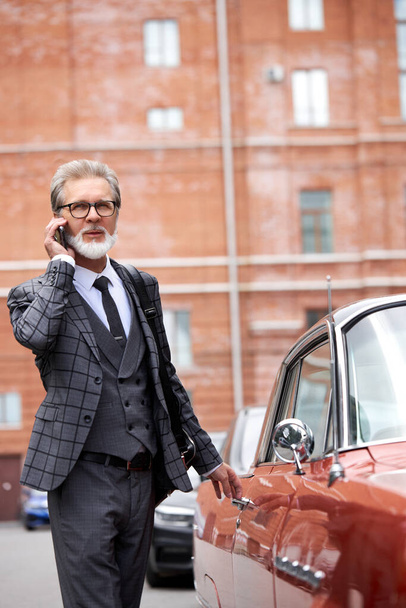 senior businessman left office building to talk on modern mobile phone in the street - Foto, Imagem
