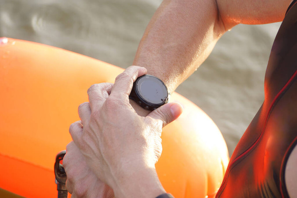 Triatleta nadador ajustando su reloj inteligente                                - Foto, imagen