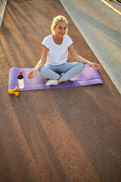 Charming woman practicing yoga on the street - Photo, Image