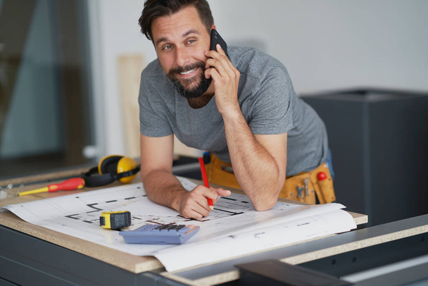  Smiling carpenter talking to a client on the phone                               - Foto, Bild
