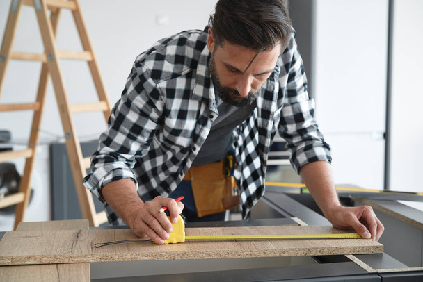 Carpinteiro medindo uma placa de corte
 - Foto, Imagem