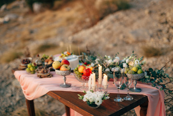 シャンパングラス、キャンドルや花の花束と結婚式のお祝いのために飾られた木製のテーブル. - 写真・画像