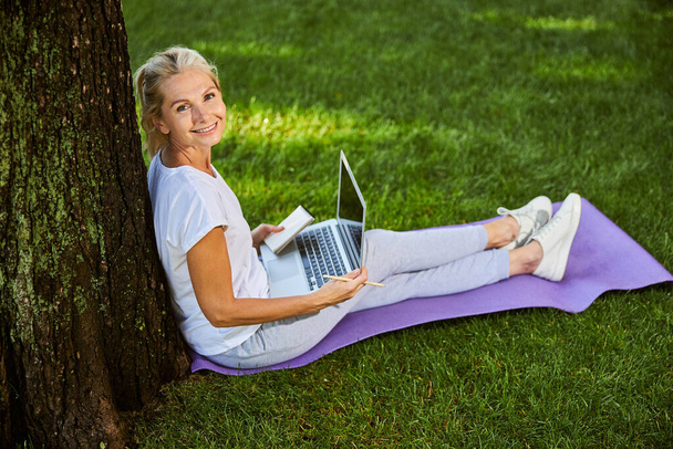 Beautiful cheerful woman using laptop in park - Fotó, kép