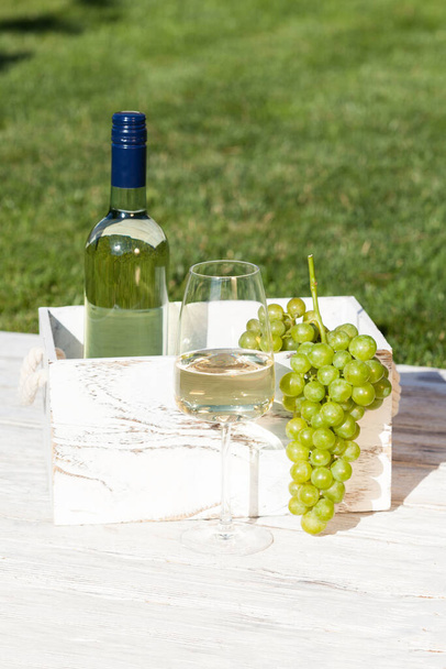 Wooden box with bottle of white wine and wineglass and grapes on wooden rustic table  - Foto, Imagem