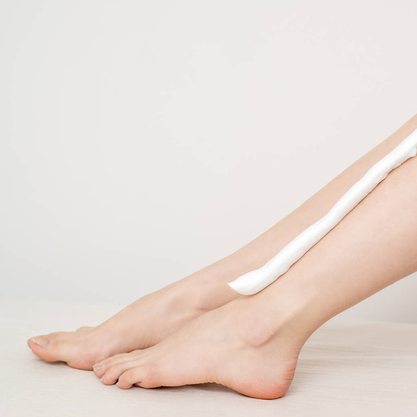 Female nice long slim bare legs with shaving foam on white background - 写真・画像