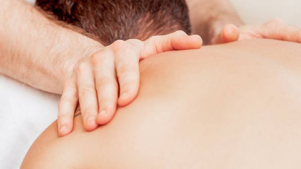 Young man receiving back massage by hands of masseur in spa beauty salon. - Photo, Image