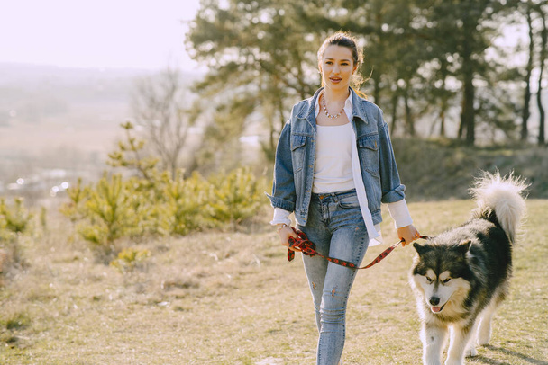 Stylish girl in a spring field with a dog - Фото, зображення