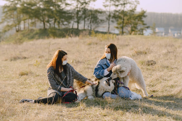 Two stylish girls in a spring field with a dog - Foto, Bild