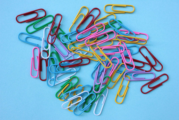 Top view of colorful paper clips on blue background with copy space. Back to school or office concept - Photo, Image