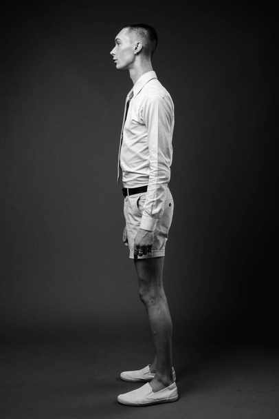Studio shot de jeune homme d'affaires androgyne beau sur fond gris en noir et blanc - Photo, image