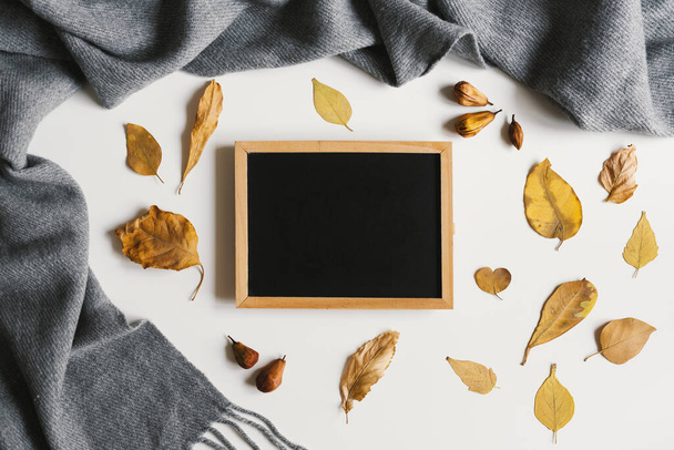 Autumn flat lay with blackboard, woolen scarf and yellow leaves on white background. Fall season, space for text, top view - Zdjęcie, obraz