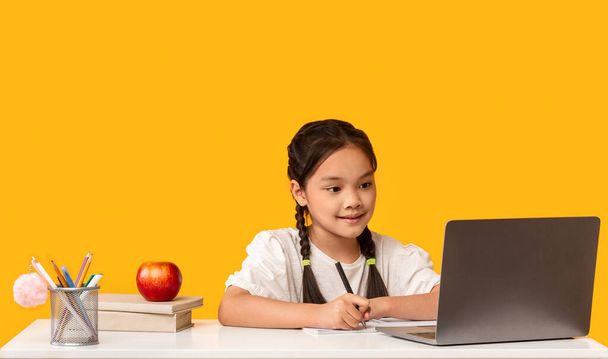 Japanese Elementary Student Girl Doing Homework at Laptop, Studio Shot - Фото, зображення
