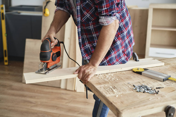 Carpenter cutting the boards to size using a jigsaw                             - Photo, image