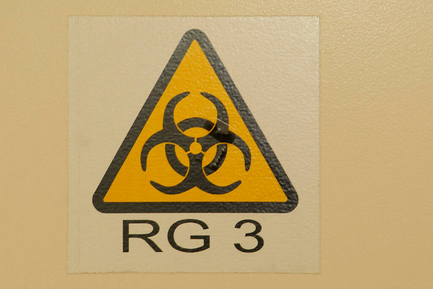 black biohazard warning sign on yellow background, RG 3, danger to health - Foto, imagen