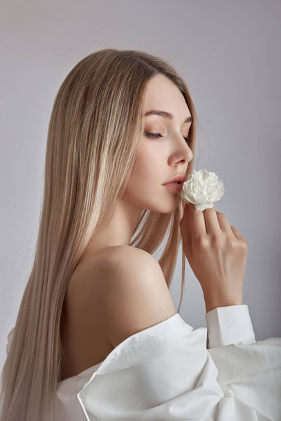 Blonde beauty woman holds white flower in hand. Beautiful soft hands and soft skin. Cosmetics for beauty hand care - Фото, зображення
