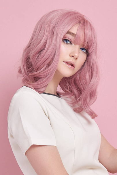 Cute girl with long pink hair, hair coloring. Beautiful woman on a pink background in a white dress. Colored hair, perfect hairstyle, beauty and care - Valokuva, kuva