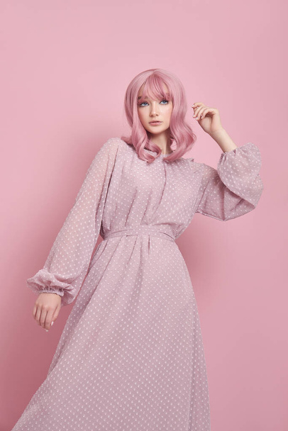 Woman with dyed pink hair in a long dress. Portrait of a girl with hair coloring at the pink wall. Perfect hairstyle and hair styling - Foto, Imagen