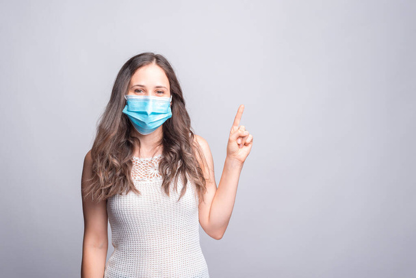 Portrait of young woman wearing medicinal mask and pointing away at copyspace - Foto, immagini