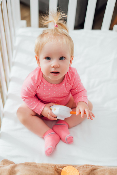赤ん坊モニターを持っている幼児の女の子のオーバーヘッドビューでクリブ  - 写真・画像