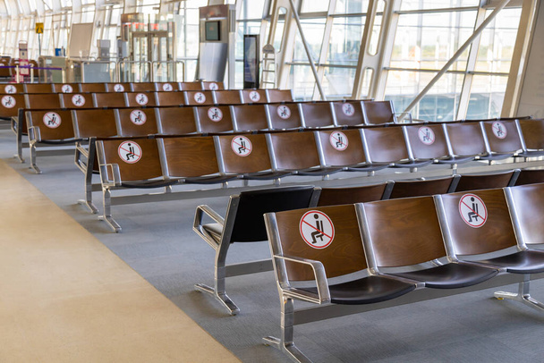 Μεταφορά στην εποχή μετά το Coronavirus. Άδεια καθίσματα αεροδρομίου με αυτοκόλλητα κοινωνικής απόστασης που πρέπει να αποτρέπουν τους ανθρώπους από το να κάθονται πολύ κοντά το ένα στο άλλο - Φωτογραφία, εικόνα