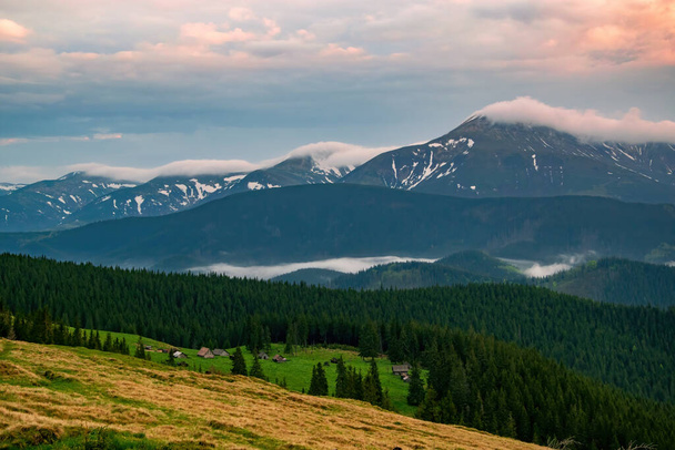Spectacular autumn evening over mountain meadow in Carpathian Mountains, Ukraine. Chornohora mountain range covered by clouds on background - Foto, Imagem