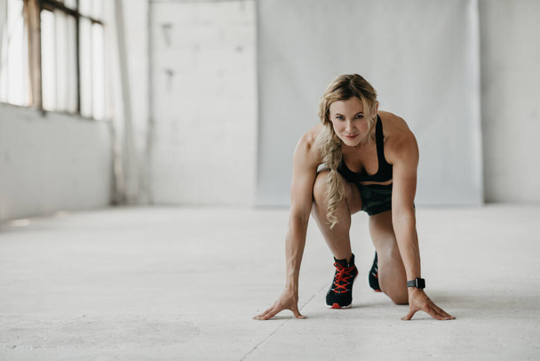 Treenaa, juokse ja aloita. Lihaksikas sovi nainen urheiluvaatteet kunto tracker käyttäessään kuntosalilla - Valokuva, kuva