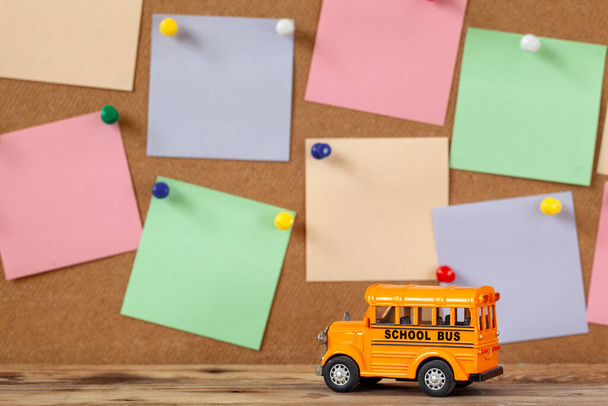 Back to school and Education concept. School bus toy with colorful sticky notes for design on wooden background. - Foto, afbeelding